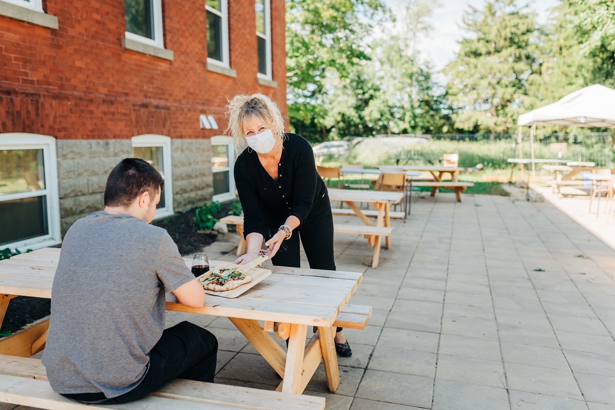 Sarah serving pizza on the patio at 1909 Culinary Academy