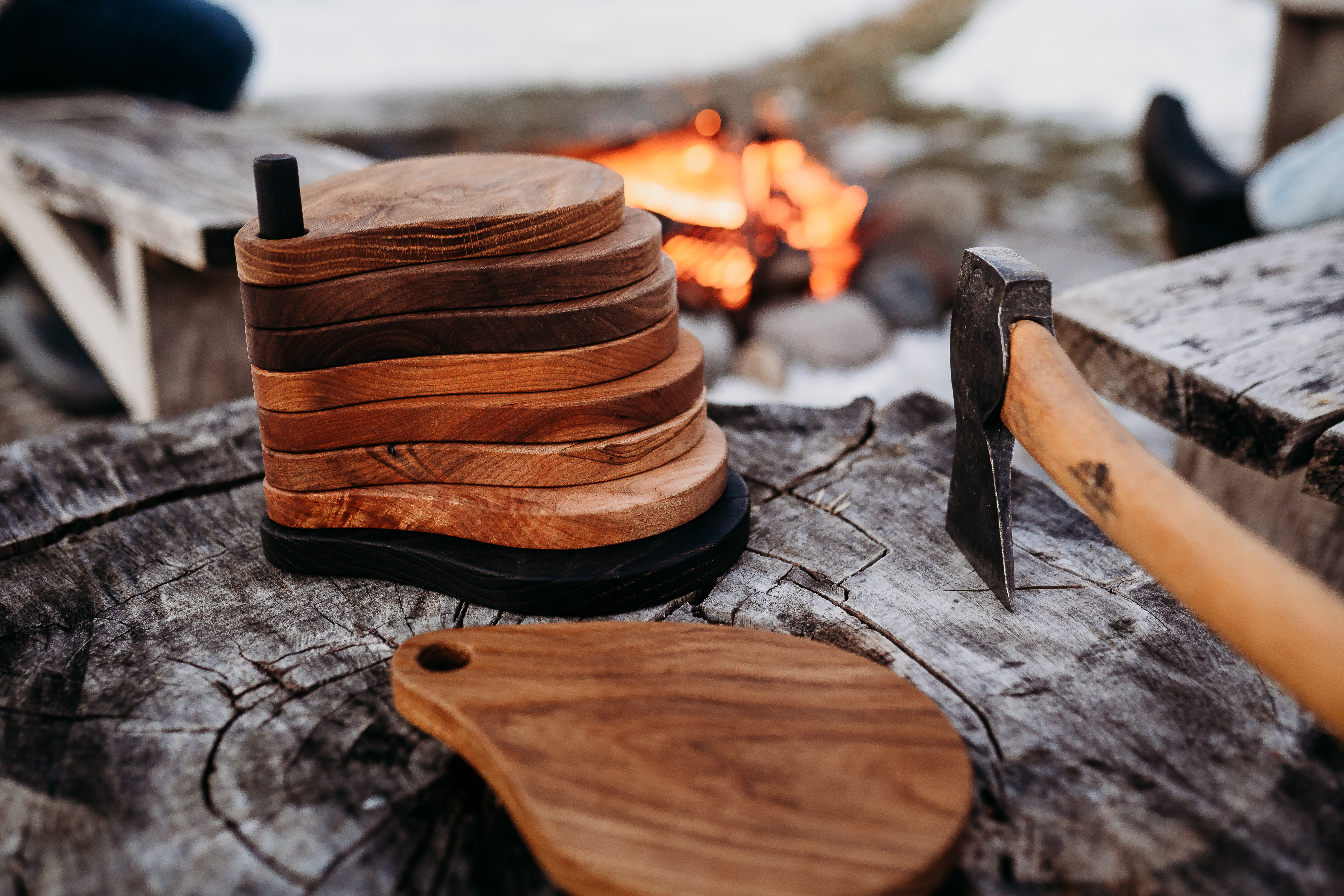Ottercreek Woodworks stacked charcuterie boards sitting on a tree stump by roaring firepit
