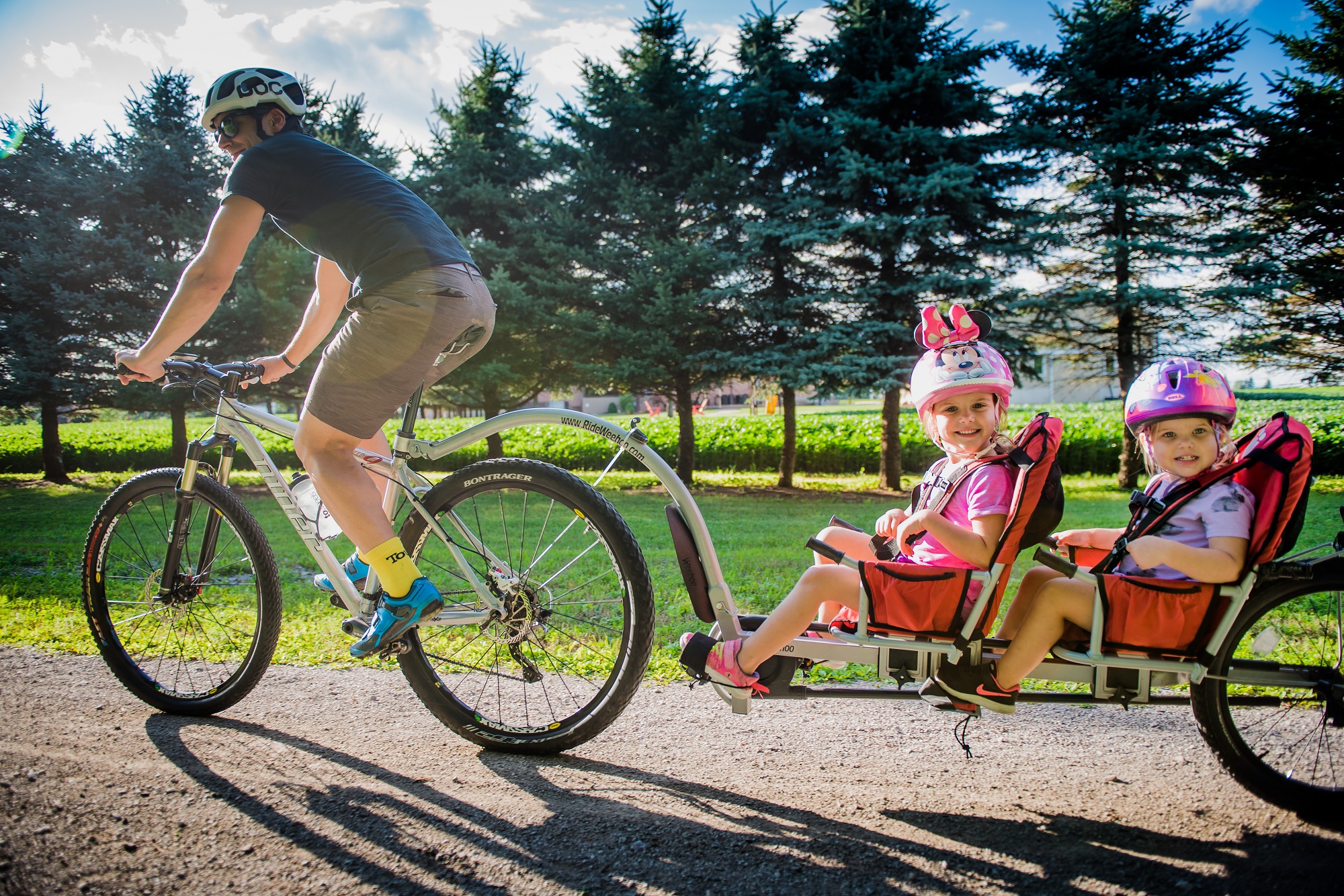 cyclist riding the trans-canada trail, pulling two kids behind him