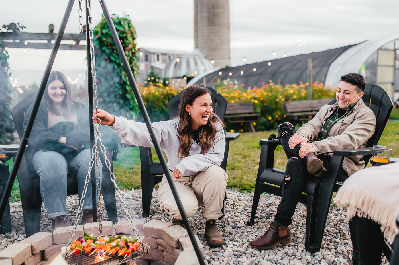 Rising Roots produce skewers roast over the fire with guests smiling, laughing