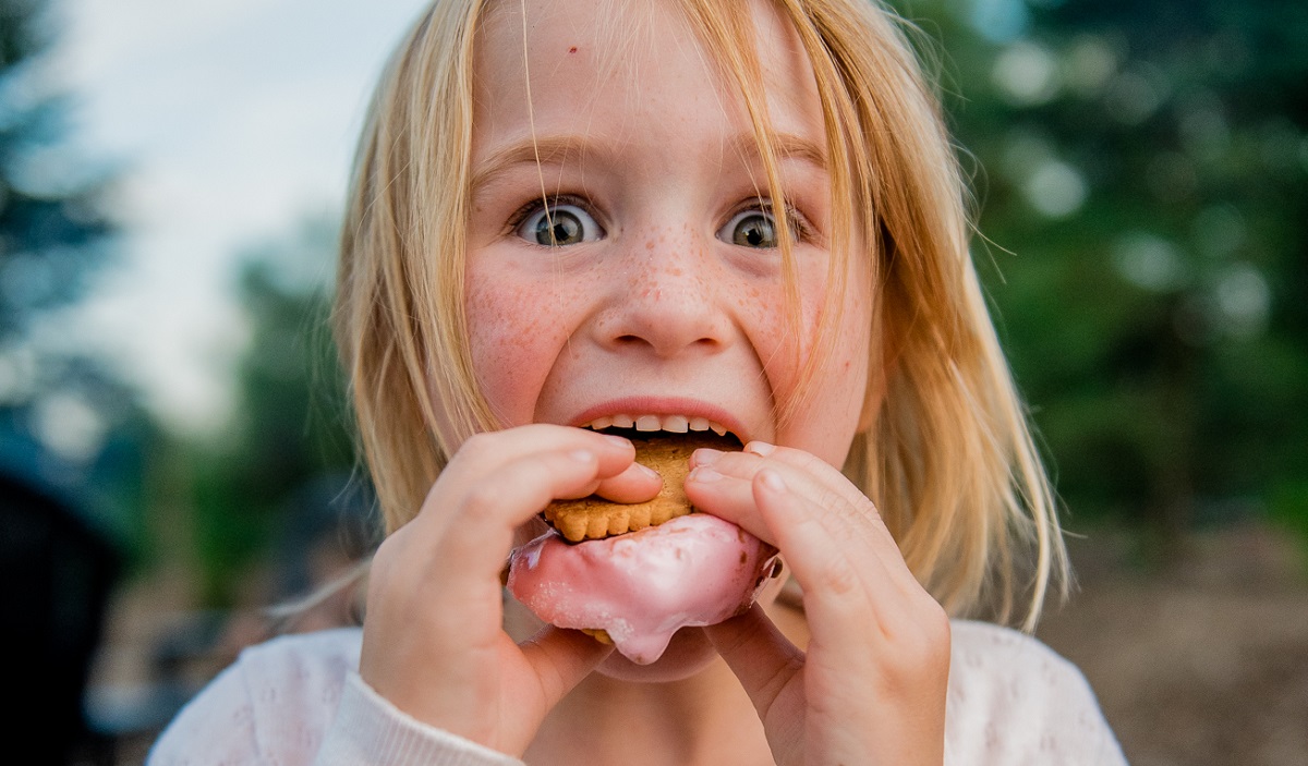 young girl taking a bite of a smore