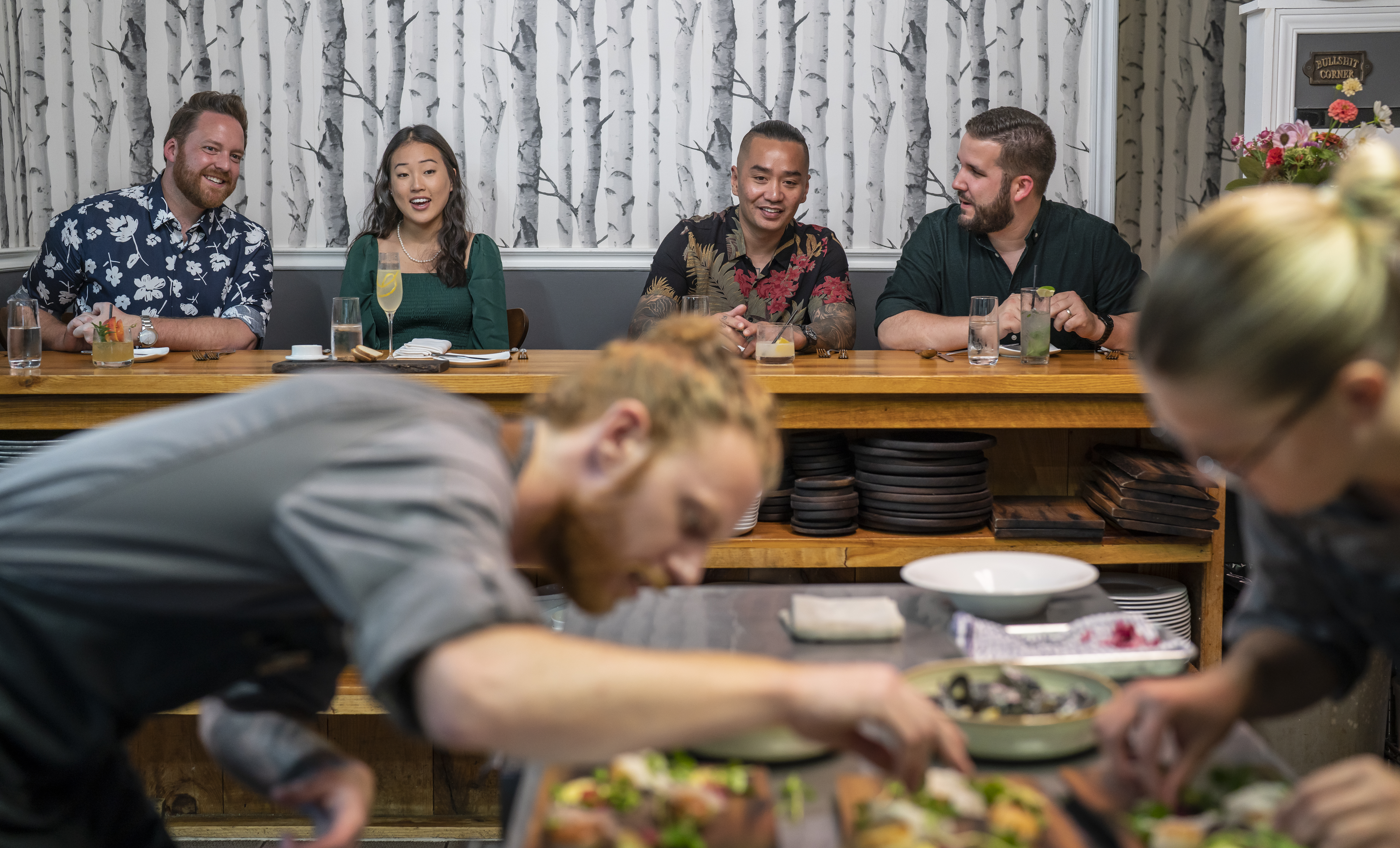 sixthirtynine guests laughing together in background as chef plates intently