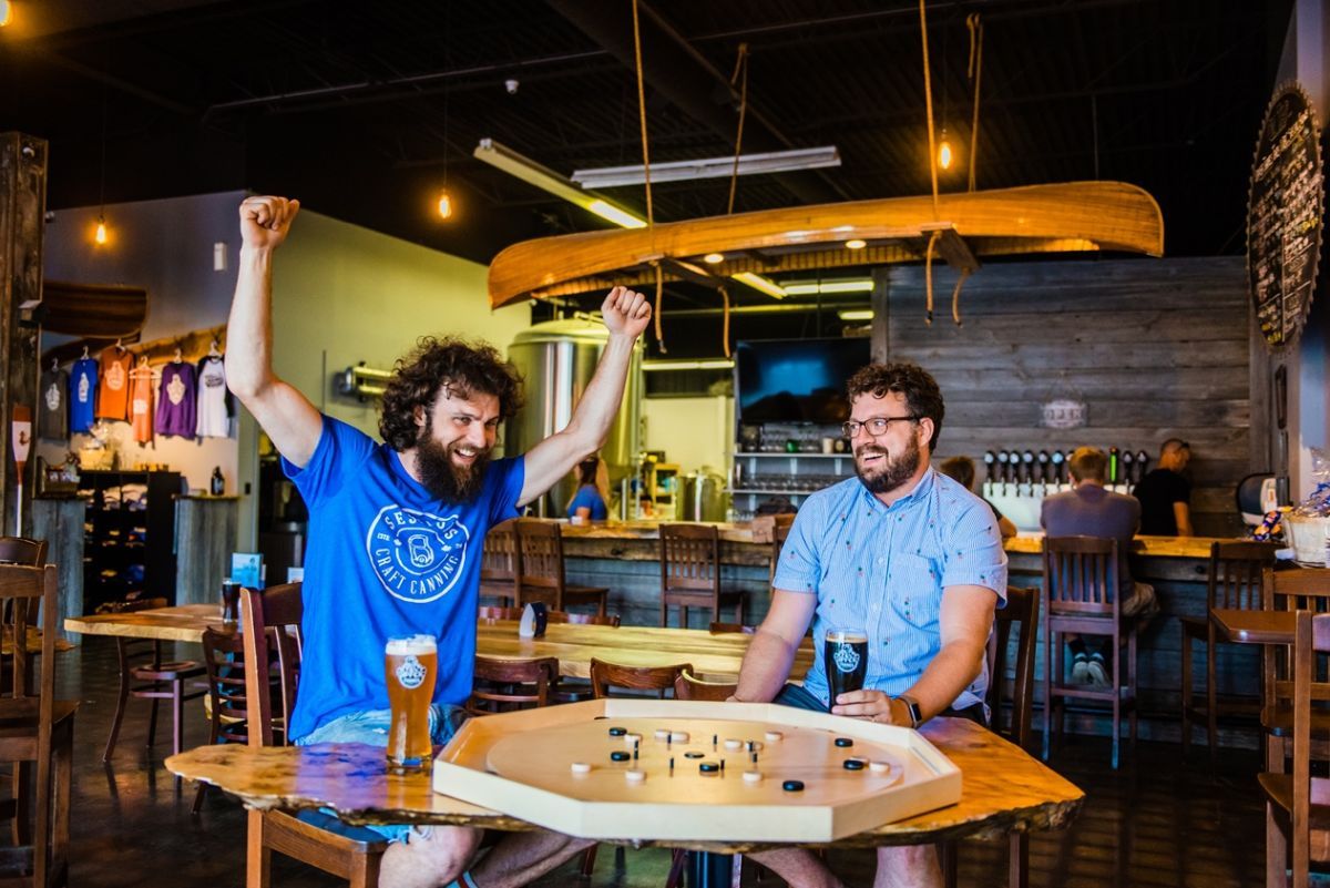 sean and drake playing crokinole, drake celebrating a win or big score