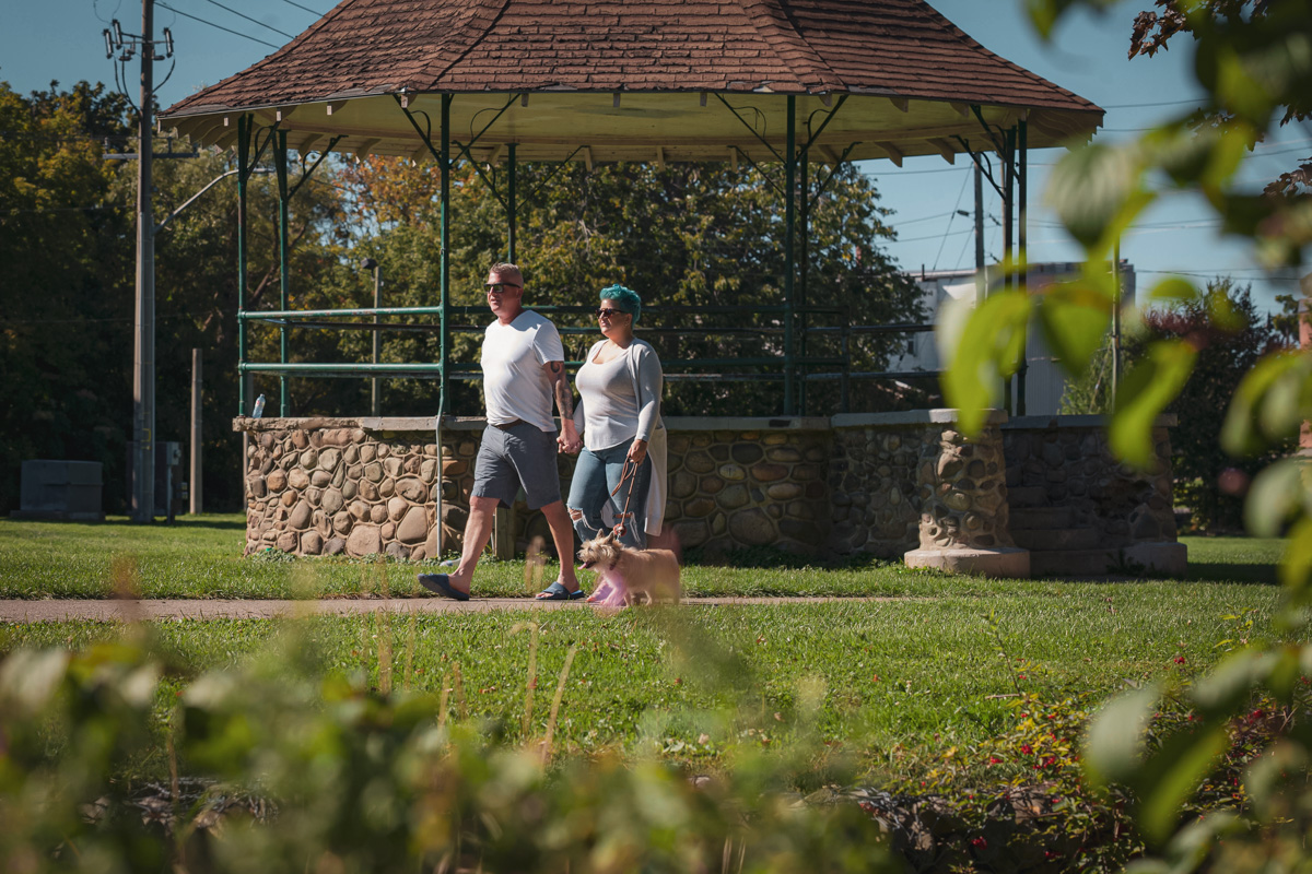 A couple strolling through the park with their small dog