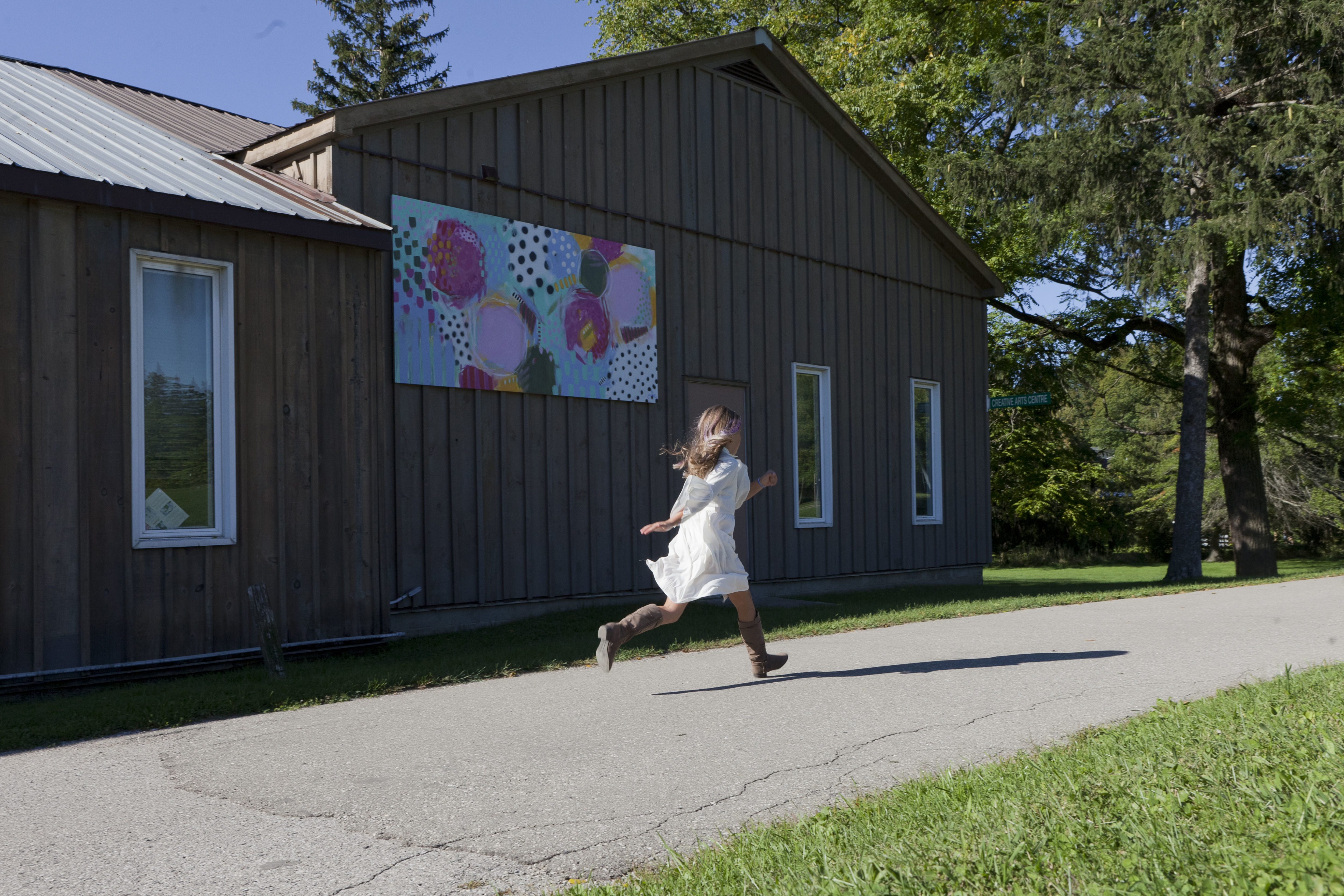 girl runs along the path at ICAC with a bright mural in the background