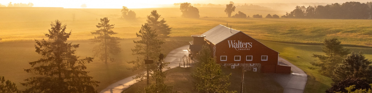 The red barn with large Walters logo sits in a rural area during golden hour